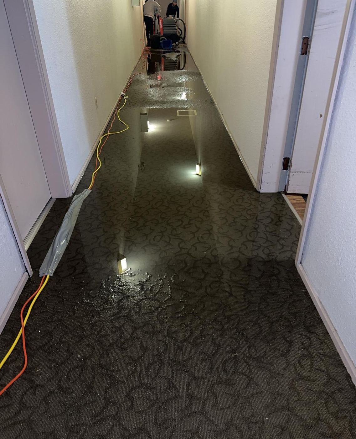 Standing water across a carpeted apartment corridor during an overnight flood response